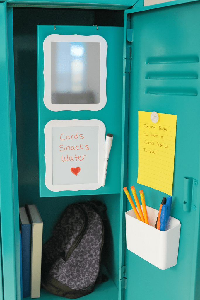 a school locker with school books, a backpack, and magnetic pen holder, mirror, whiteboard and pen, and two magnets